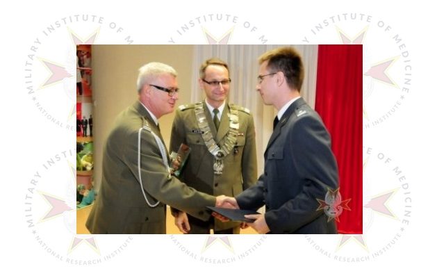 Dyrektor WIM podczas uroczystości wręczania nagrody na drugim planie grafiki półprzezroczyste logotypy WIM.