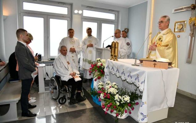 Msza święta z okazji dnia chorego w kaplicy szpitalnej Wojskowego Instytutu Medycznego. Zdjęcie biskupa polowego podczas odprawianej mszy. Obok ksiadz na wózku uczestniczy w mszy, obok niego modlący się księża.