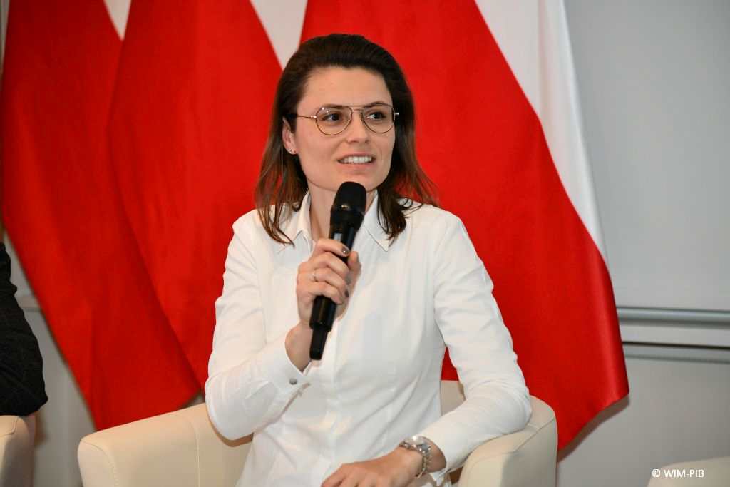 Dr hab. n.  prawnych Aneta Łazarska siedzi z mikrofonem w dłoni podczas panelu dyskusyjnego.