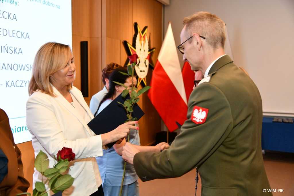 Dyrektor WIM Grzegorz Gielerak i Lidia Wojda wręczają odznaczenia i dyplomy.