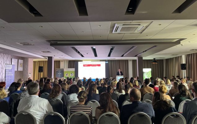Słuchacze siedzący na sali podczas wykładu na konferencji. Widok z końca sali.
