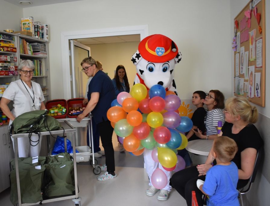 Maskotka Marshalla z Psiego patrolu z balonami wchodzi do sali pacjentów.