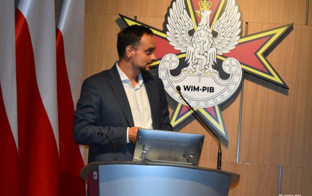 Prelegent konferencji przy mównicy.