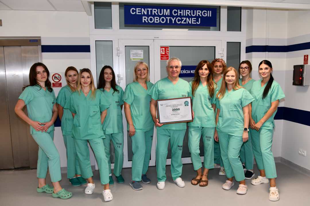 Zdjęcie grupowe. Jacek Doniec trzyma dyplom 500 wykonanych operacji robotem da vinci.