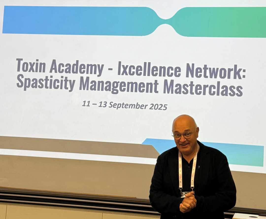 Profesor Serder Kocer podczas wykładu. Za nim plansza z nazwą kursu Spasticity Management Masterclass.