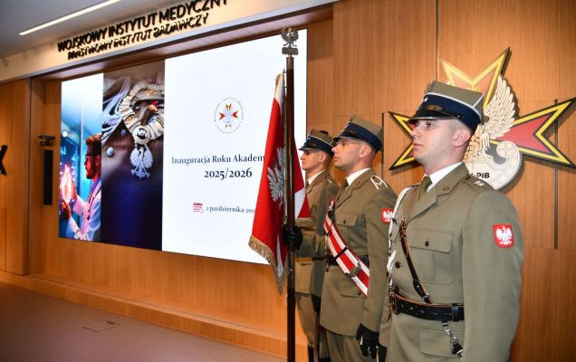 Inauguracja Roku Akademickiego w WIm-PIB. Aula WIM-PIB, trzech żołnierzy w mundurach galowych stoi na baczność z sztandarem Polski, obok nich wyświetlony napis Inauguracja Roku Akademickiego 2025/2026.