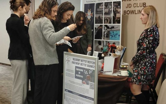 Grupa studentów i studentek przyglądająca się ofercie stoiska WIM-PIB.