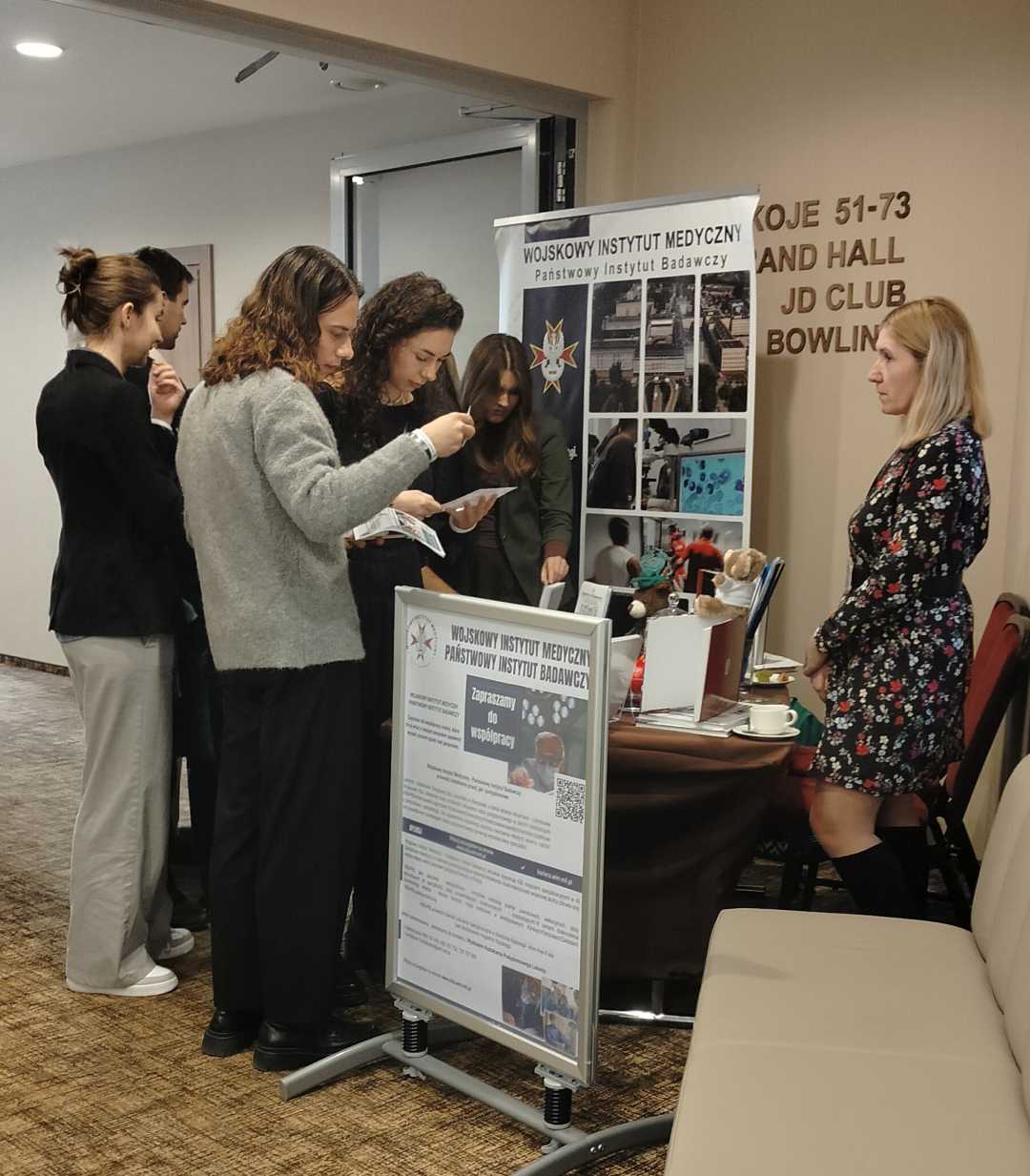 Grupa studentów i studentek przyglądająca się ofercie stoiska WIM-PIB.