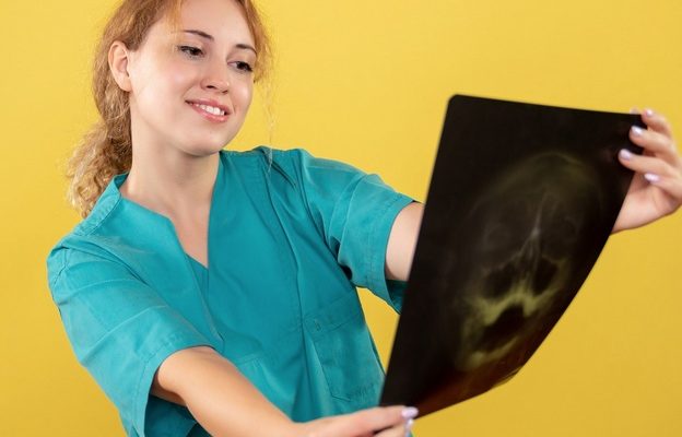 Widok z przodu kobieta lekarz w koszuli medycznej trzymającej zdj ecie RTG.