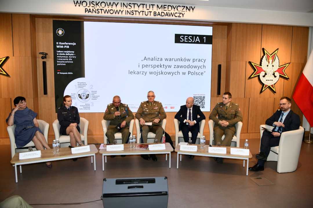 Uczestnicy siedzący w fotelach podczas panelu dyskusyjnego, za ich plecami wyświetlony fragment prezentacji.