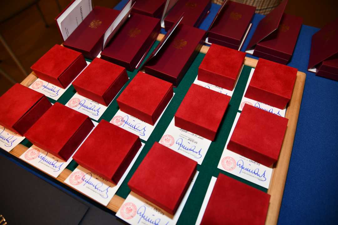 Odznaki w czerwonych aksamitnych pudełkach ułożone obok siebie na stole z niebieskim płótnem.