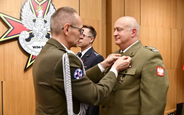 Dyrektor WIM przypina pracownikowi WIM odznaczenie.