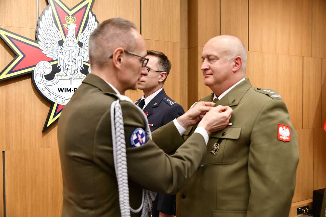 Dyrektor WIM przypina pracownikowi WIM odznaczenie.