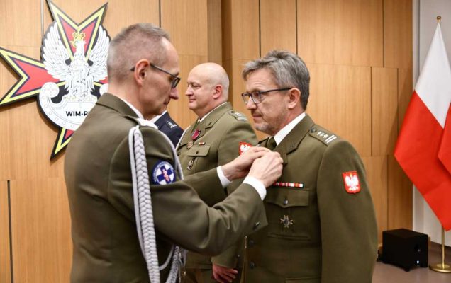 Dyrektor WIM przypina pracownikowi WIM odznaczenie.