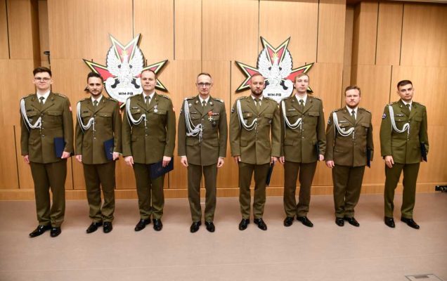 Dyrektor WIM i awansowani pracownicy ubrani w mundury wojskowe pozują do zdjęcia.
