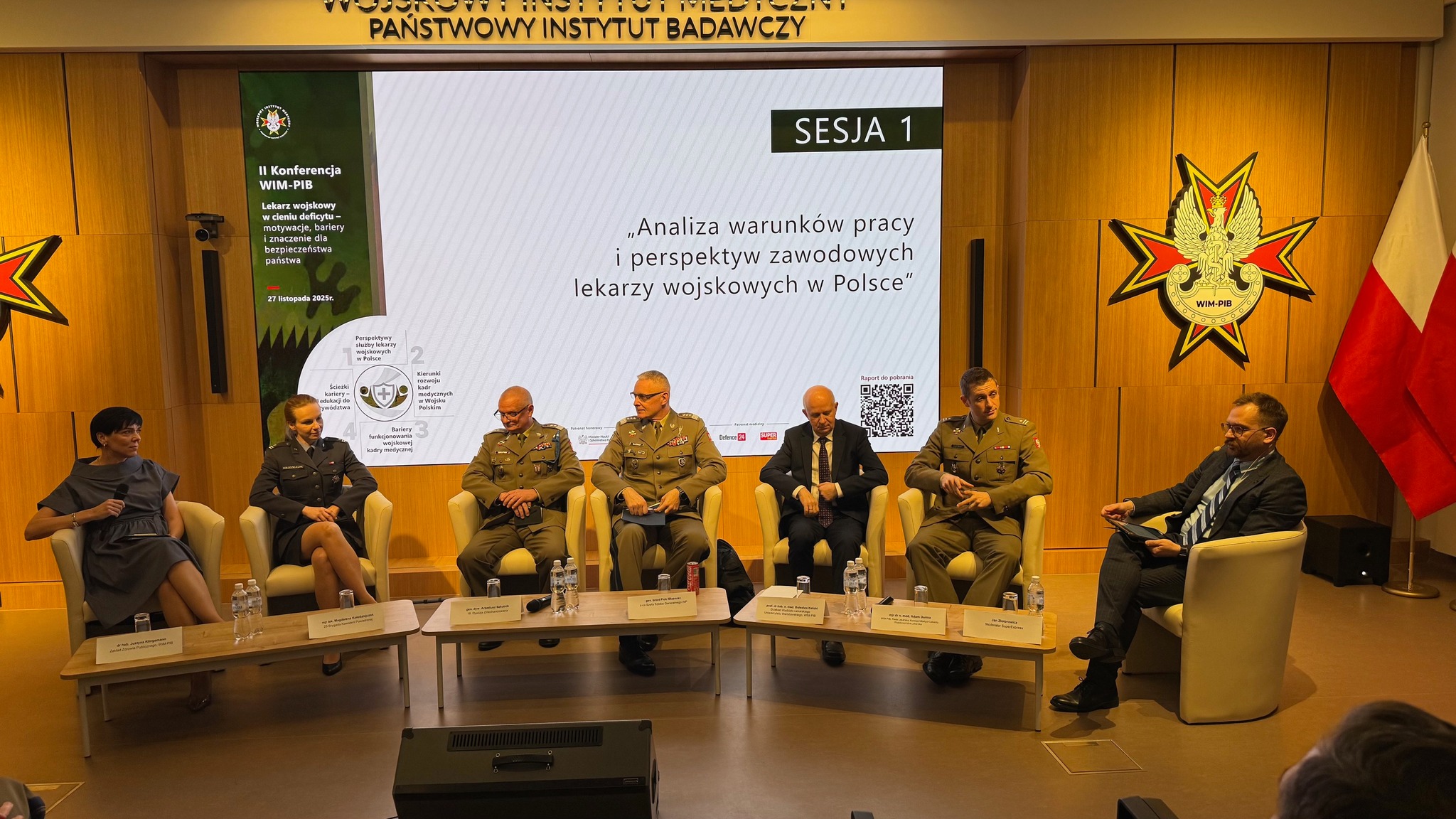 Uczestnicy siedzący w fotelach podczas panelu dyskusyjnego, za ich plecami wyświetlony fragment prezentacji.