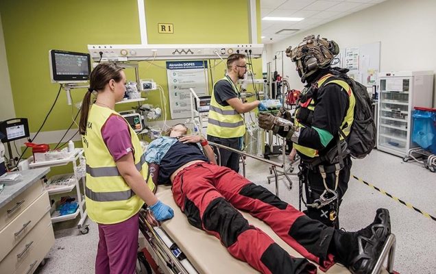Ratownicy medyczni przy leżącym na łóżku w szpitalu polowym rannym.