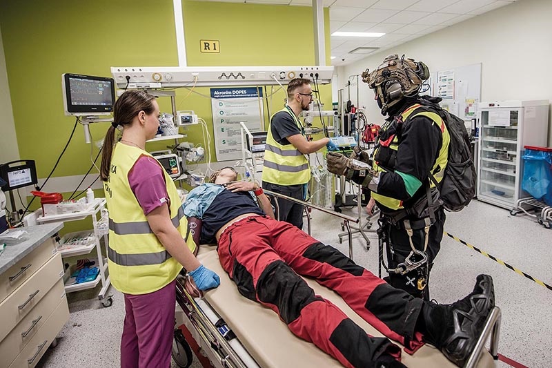Ratownicy medyczni przy leżącym na łóżku w szpitalu polowym rannym.