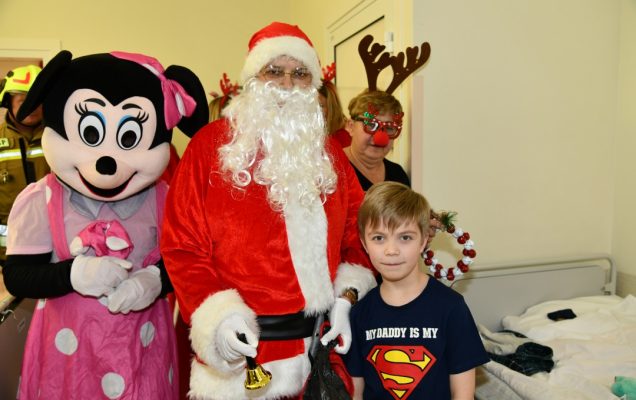 Kilkuletni chłopiec w towarzystwie świętego Mikołaja i jego pomocników.