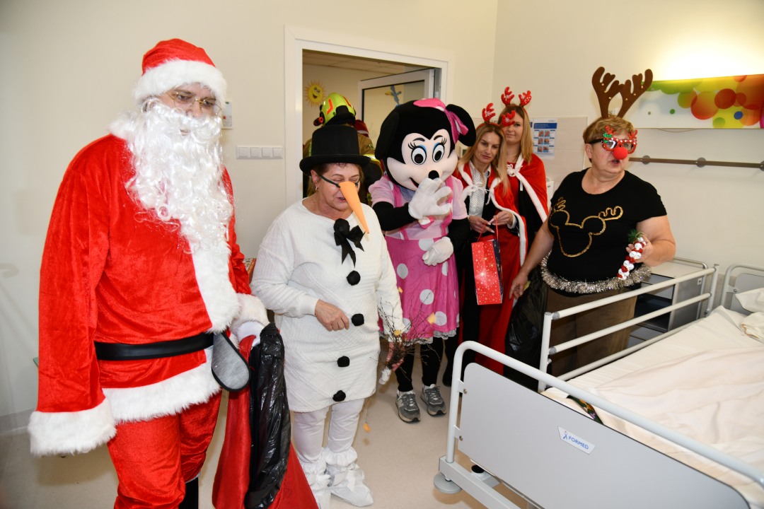 Święty Mikołaj i jego pomocnicy wchodzą do sali szpitalnej.