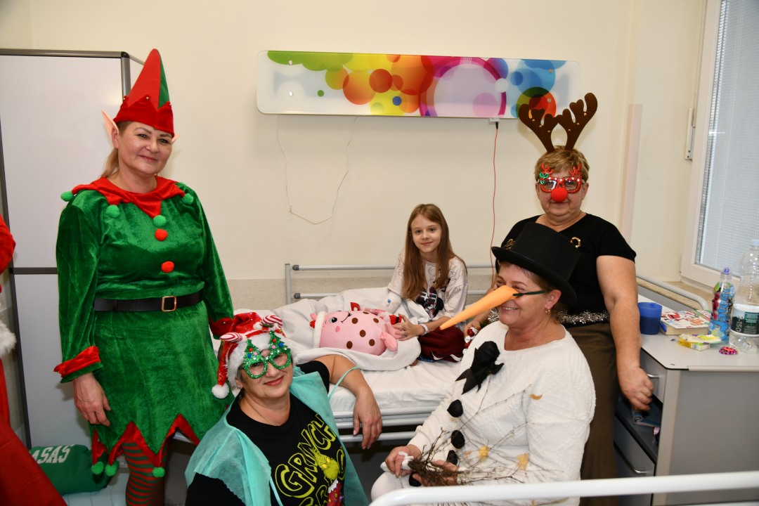 Pomocniczki świętego mikołaja na sali szpitalnej z pacjentami.