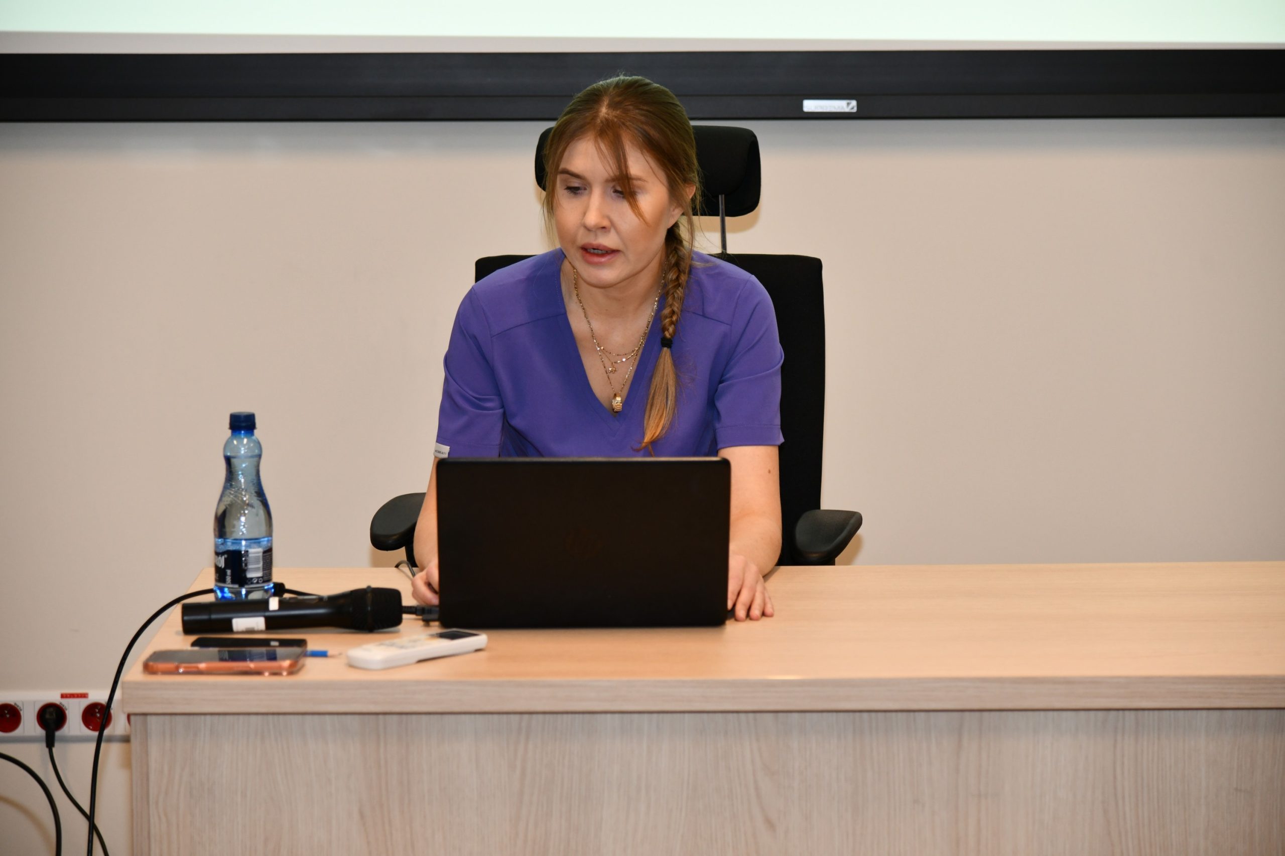 Ppłk dr n. med. Agnieszka Grabińska, siedzi przy biurku z laptopem i prowadzi wykład.