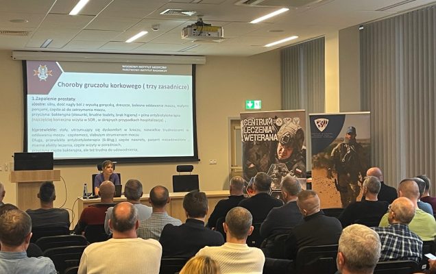 Ujęcie z tyłu. Siedzący uczestnicy na sali słuchający wykładu.