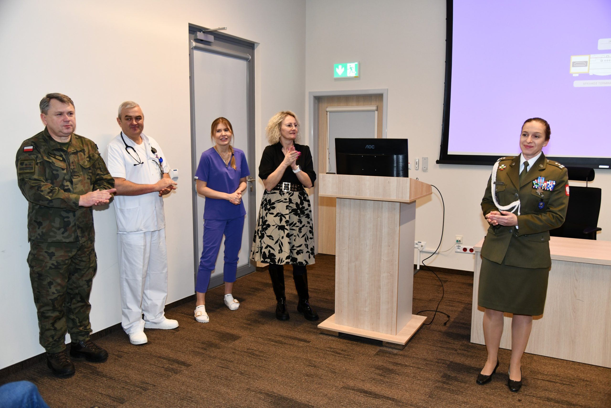 Pracownicy WIM stoją przy mównicy dziękując za uczestnictwo.