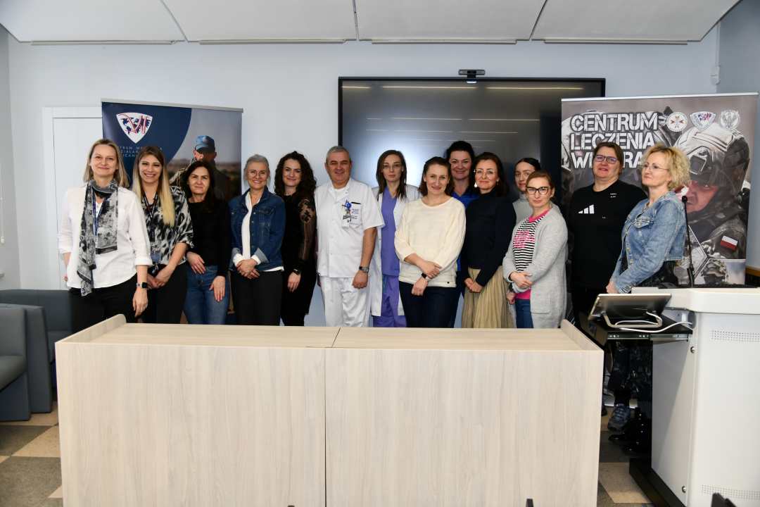 Pracownicy Centrum Leczenia Weterana w sali wykładowej pozują do wspólnego zdjęcia.