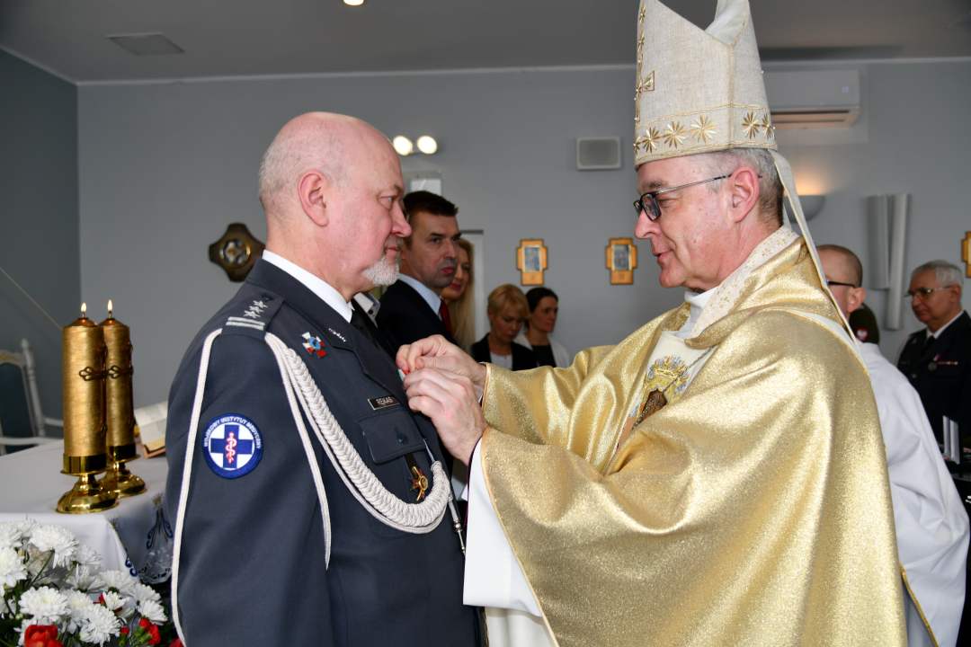 Biskup przypina medal profesorowi Markowi Rękasowi.