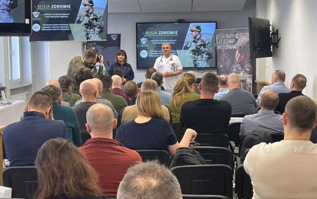 Ujęcie z tyłu sali na słuchaczy i prelegentów.