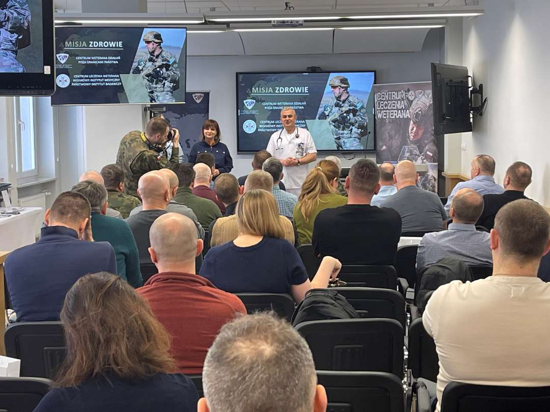 Ujęcie z tyłu sali na słuchaczy i prelegentów.