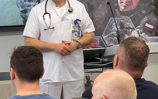 Jarosław Swistak przy mównicy podczas wykładu, za nim ekran z wyświetlaną prezentacją.