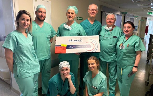 Członkowie zespołu operacyjnego w strojach operacyjnych. Operator po środku trzyma tablicę z certyfikatem Extenso.