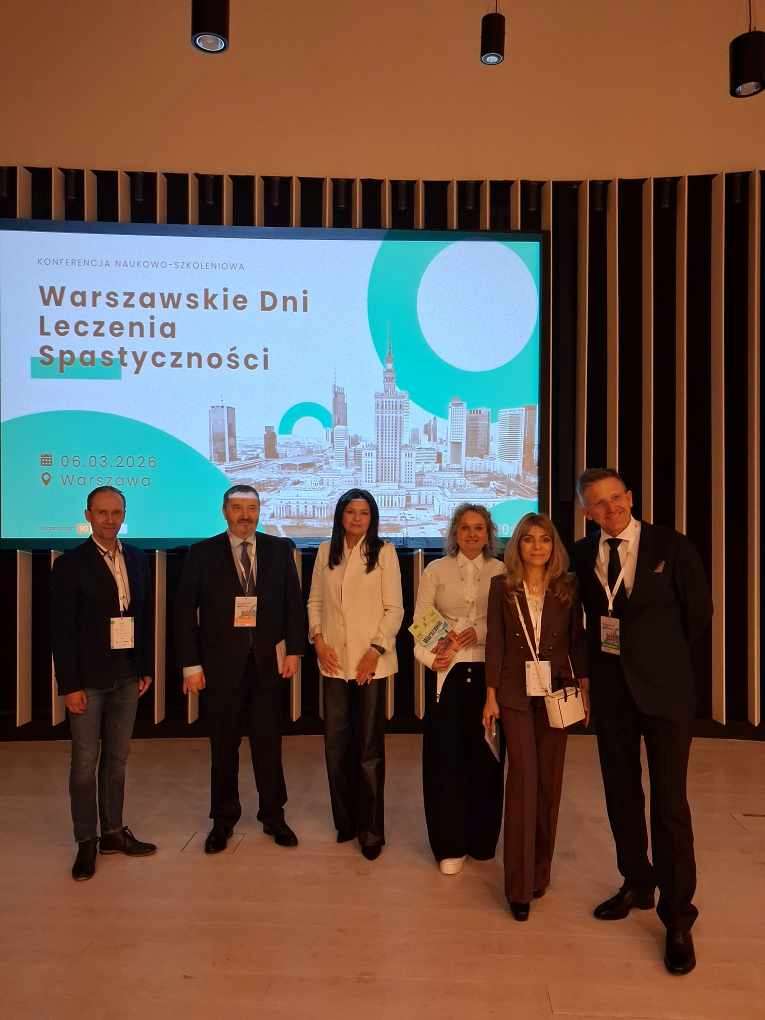 Prelegenci pozują do zdjęcia z a nimi na wyświetlaczu plansza wydarzenia.