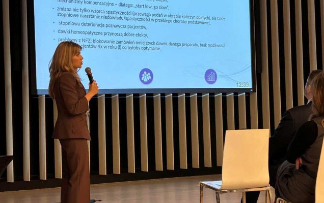 Katarzyna Gniadek-Olejniczak prowadzi prelekcję. Za nią wyświetlacz ze slajdem prezentacji.