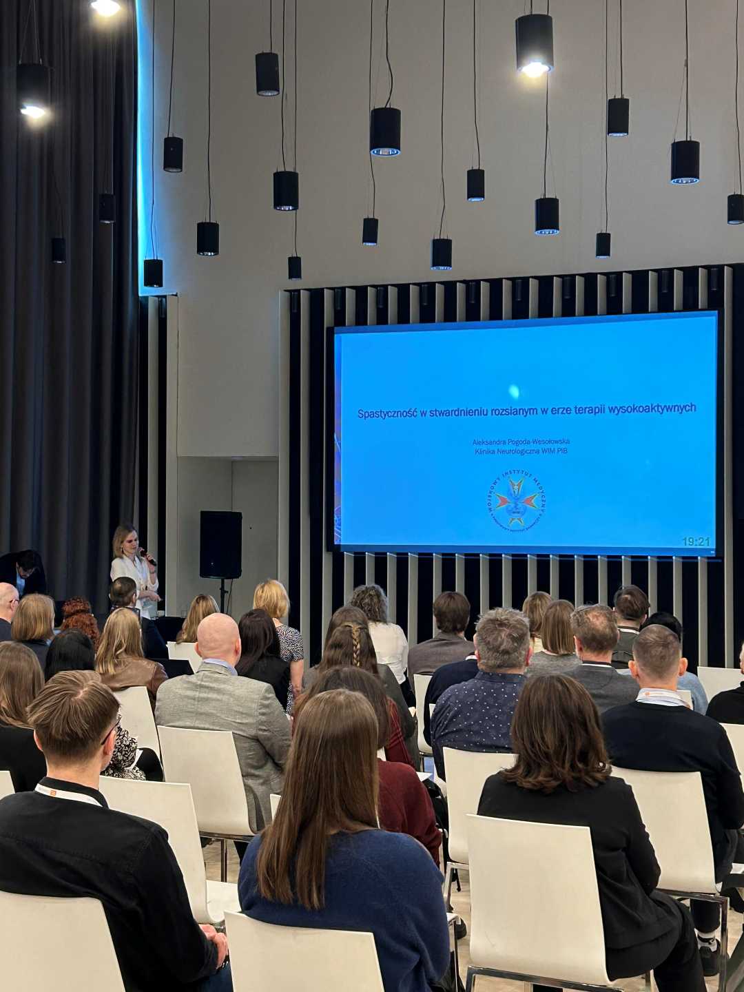 Ujęcie z tyłu sali słuchaczy podczas wykładu na sali konferencyjnej.