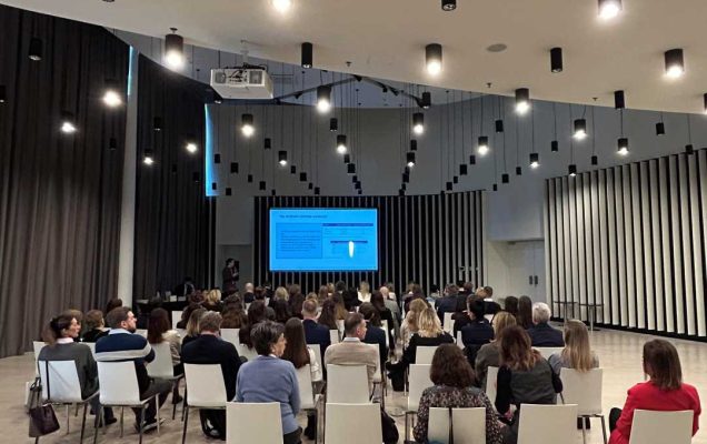 Ujęcie z tyłu sali słuchaczy podczas wykładu na sali konferencyjnej.