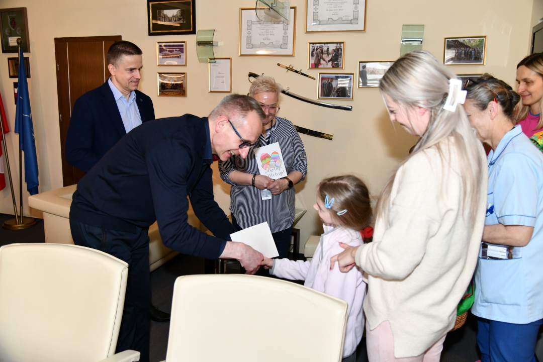 Dyrektor w swoim gabinecie odbiera kartki z życzeniami od dzieci.