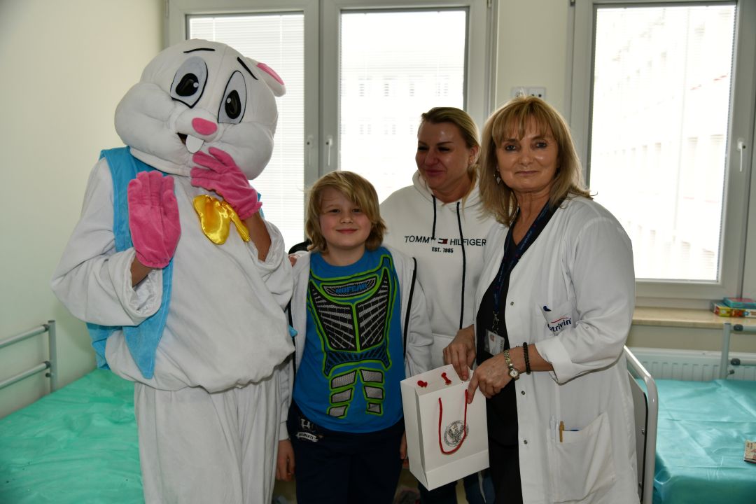 Zajączek wielkanocny w sali szpitalnej z młodym pacjentem i pracownikami kliniki pediatrycznej.