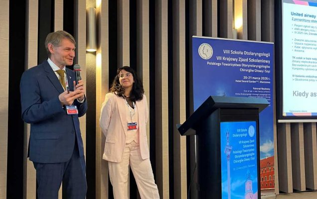 Prelegent i prelegentka na scenie podczas prezentacji. Mężczyzna trzyma mikrofon w ręku.