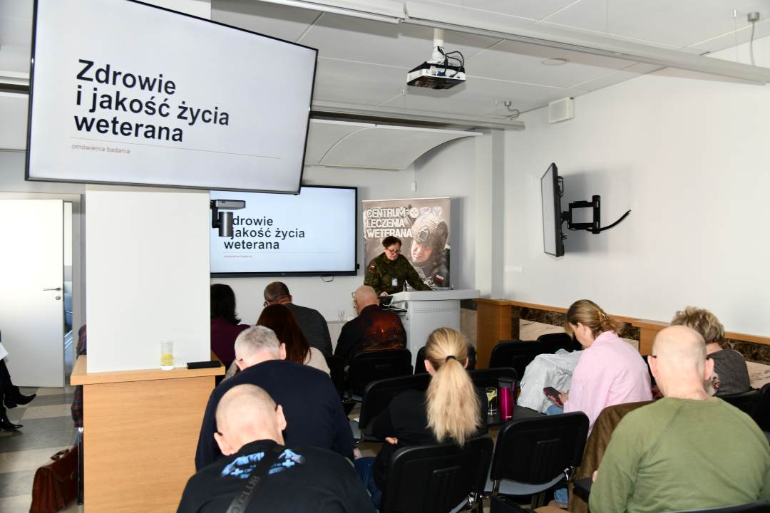 Ujęcie z tyłu sali na słuchaczy wykładu i prowadzącą wykład Barbarę Betiuk.