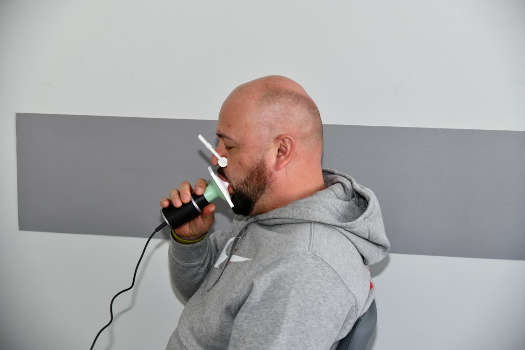 Mężczyzna trzyma w ustach urządzenie do spirometrii.