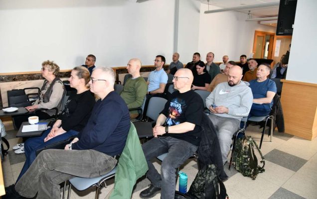 Siedzący słuchacze na sali wykładowej.