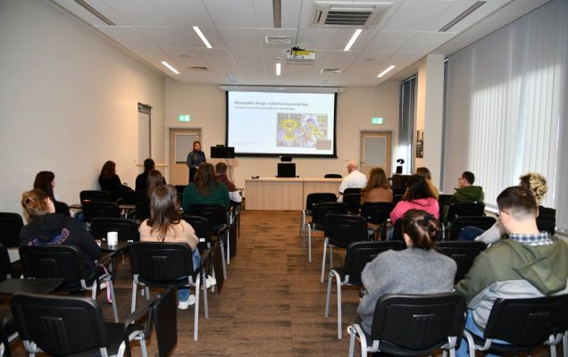 Ujęcie z tyłu sali na słuchaczy i Urszulę Karczmarczyk podczas wykładu.