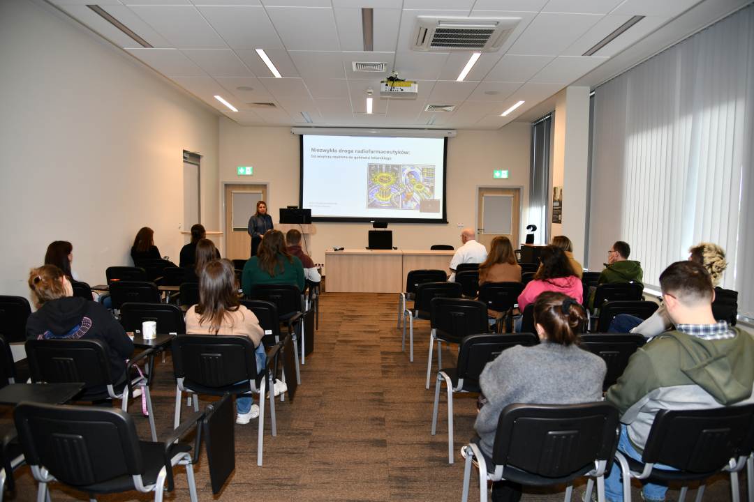 Ujęcie z tyłu sali na słuchaczy i Urszulę Karczmarczyk podczas wykładu.