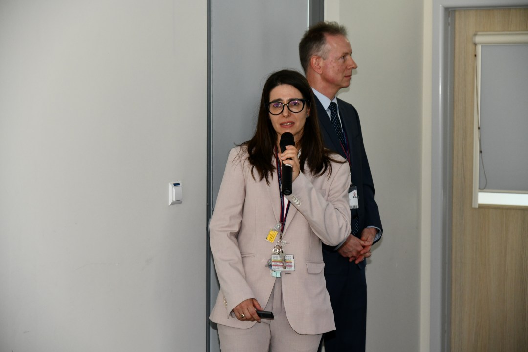 Prelegentka z mikrofonem w reku prowadzi prezentację.