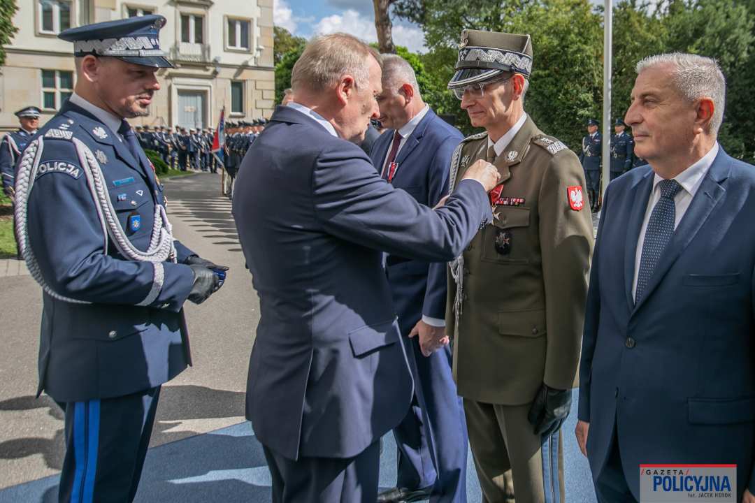 Czesław Mroczek przypina Dyrektorowi WIM medal przed gmachem policji.