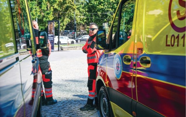 Ratownicy medyczni stojący pomiędzy dwoma ambulansami medycznymi.