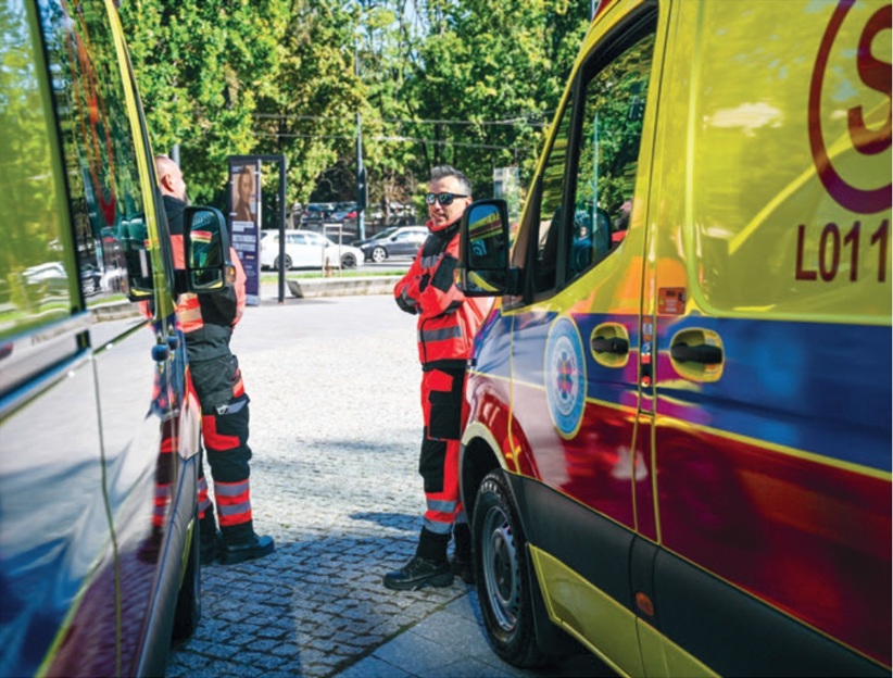 Ratownicy medyczni stojący pomiędzy dwoma ambulansami medycznymi.